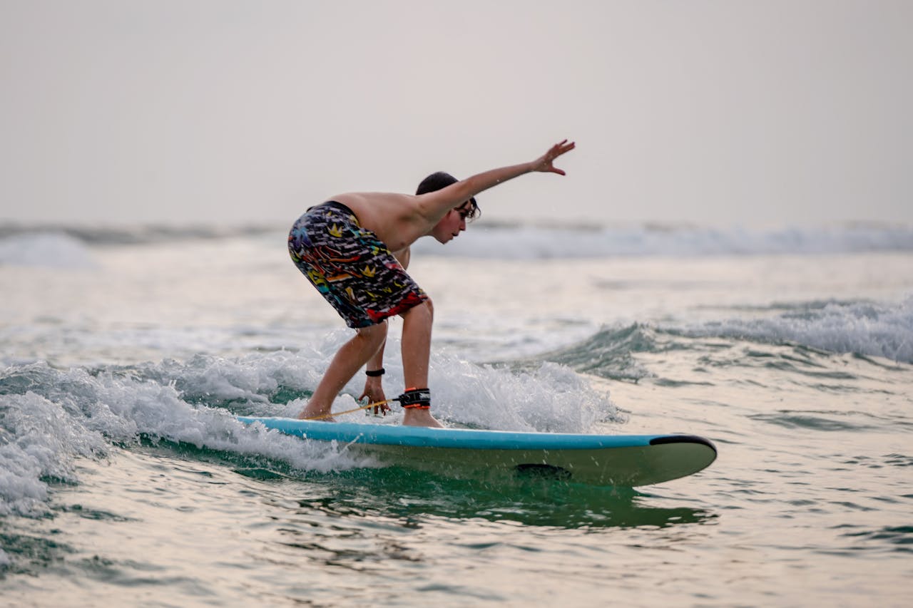 A boy skillfully surfs on a calm ocean wave in Dambulla, Sri Lanka.